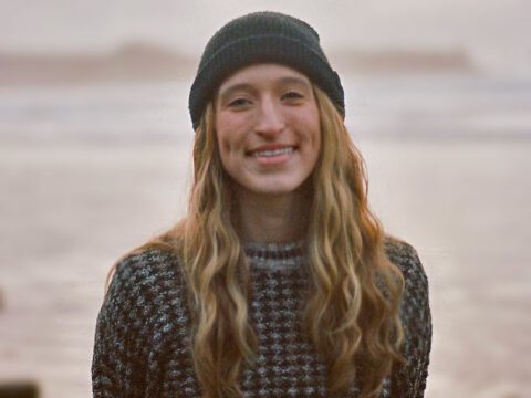 Smiling woman in gray beanie hat.