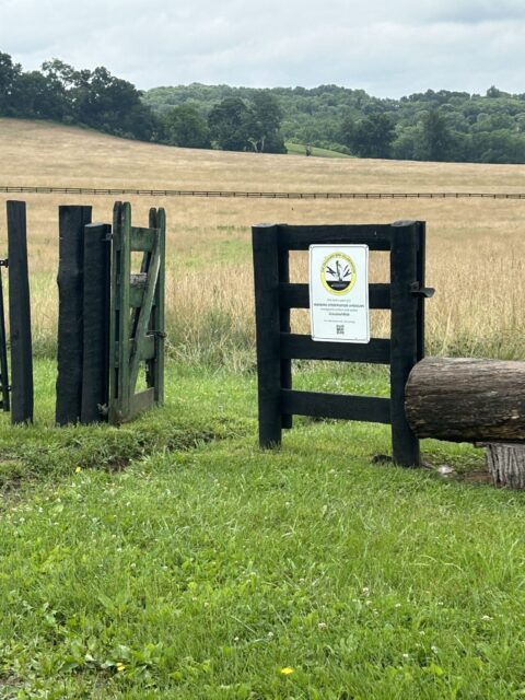 A sign on a fence around a grassland